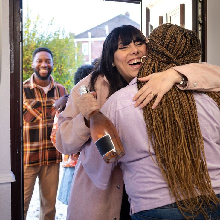 A woman excitedly arriving at her friend's house and being greeted with a friendly hug.