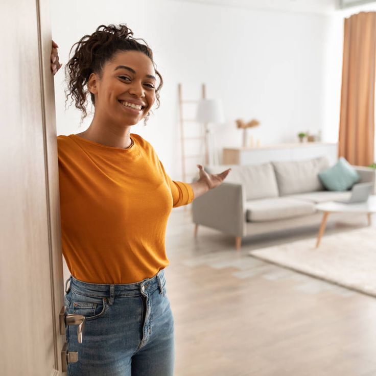 Cheerful woman opening her front door to warmly welcome family and friends while hosting guests