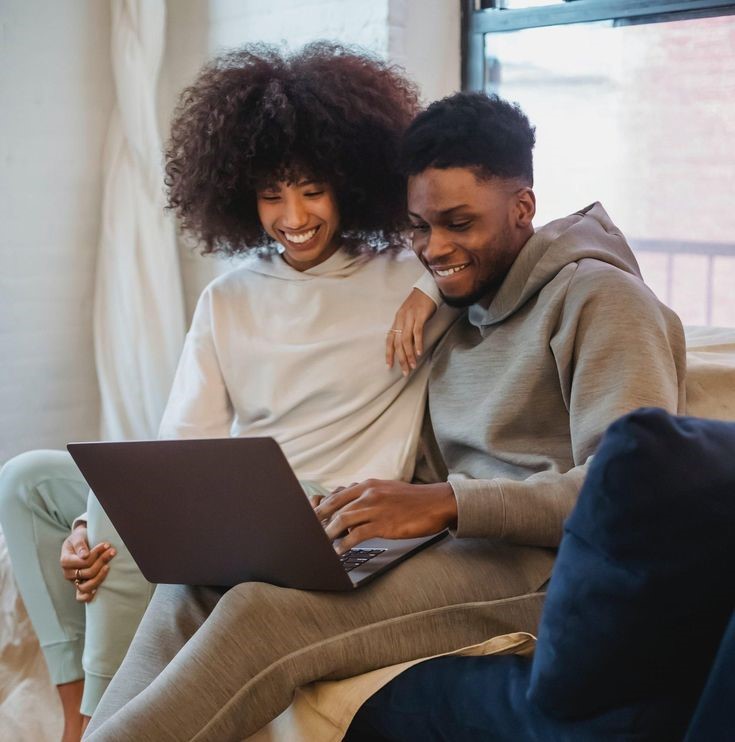 Couple planning their destination wedding budget using a laptop