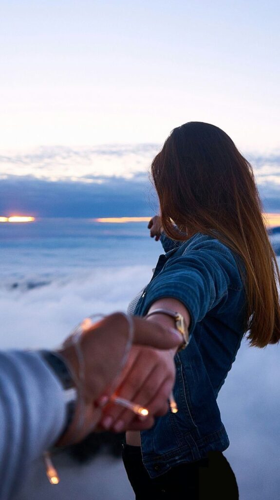 Couple Holding Hands Together While Strolling On A Beach