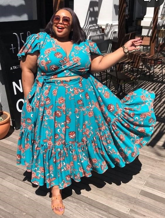 Plus-size woman wearing a flowing floral maxi dress and smiling confidently outdoors