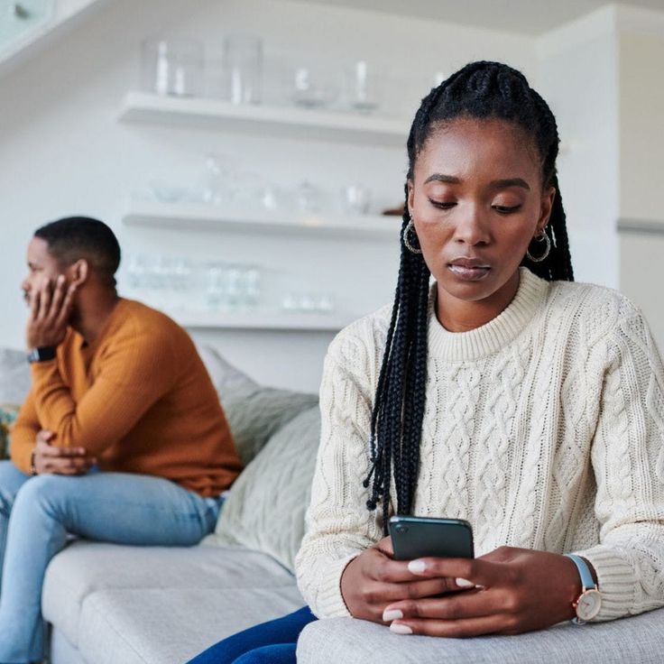 Couple sitting on the same couch but appearing sad and disconnected