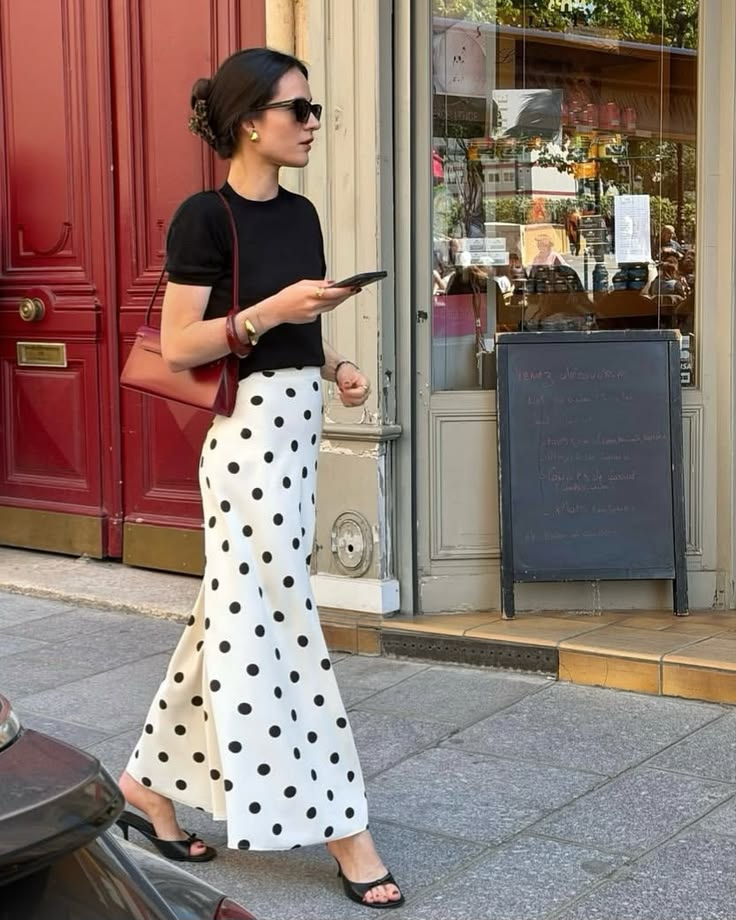 woman in a polka dot skirt holding a phone illustrating petite fashion rule