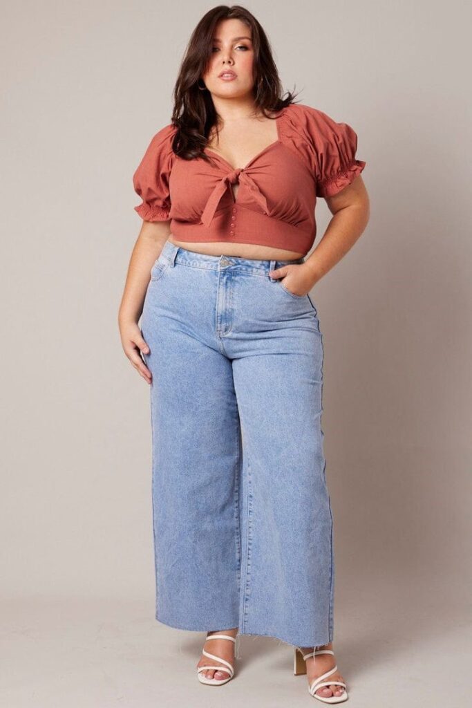 
Plus-size woman wearing a crop top and high-waisted jeans.