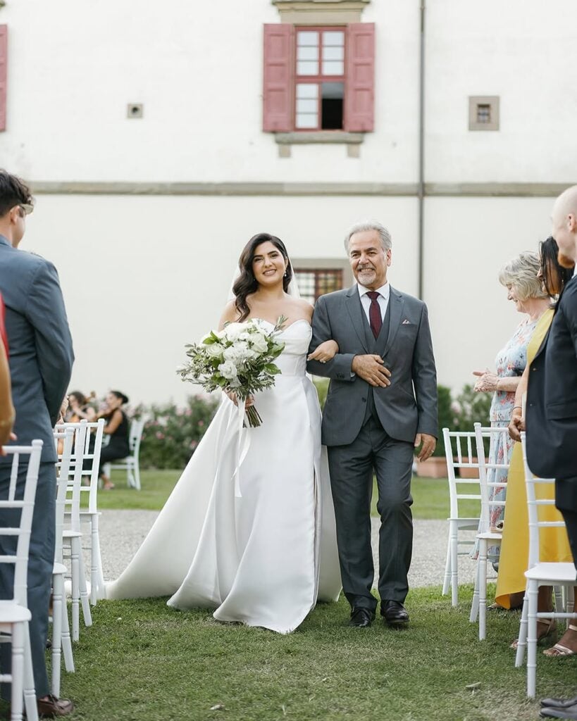 A bride walking down the aisle with her father as he holds her hand