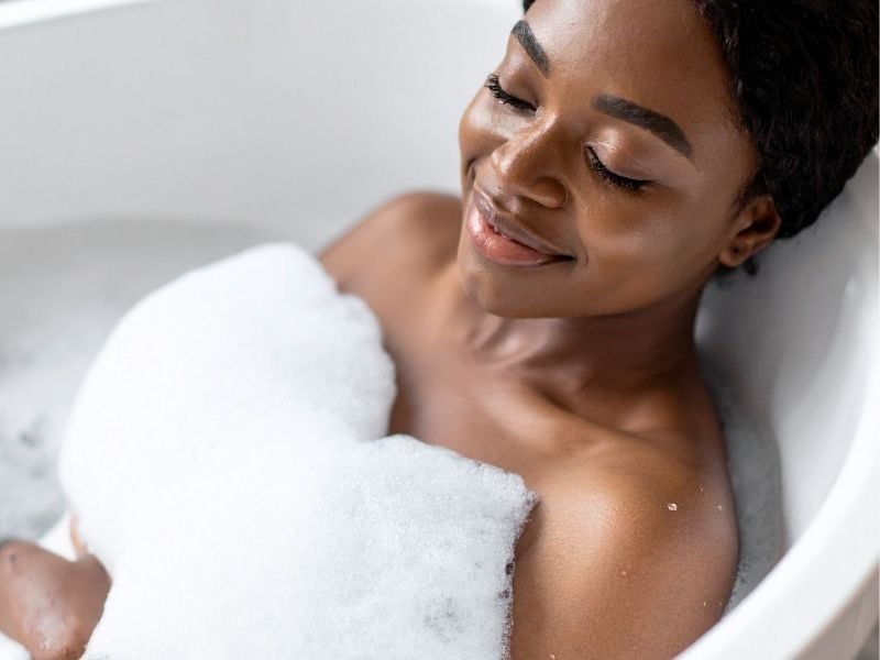 A woman soaks herself in a bathtub as she is relaxing