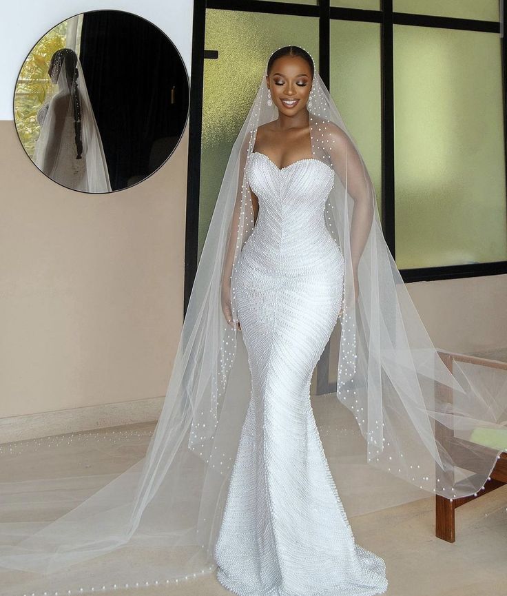 Bride wearing a fitted strapless minimalist mermaid wedding dress with a long pearl trimmed cathedral veil.