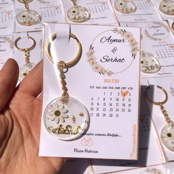 Personalized wedding favor featuring a daisy resin keychain attached to a custom mini calendar card with the couple's names and wedding date.